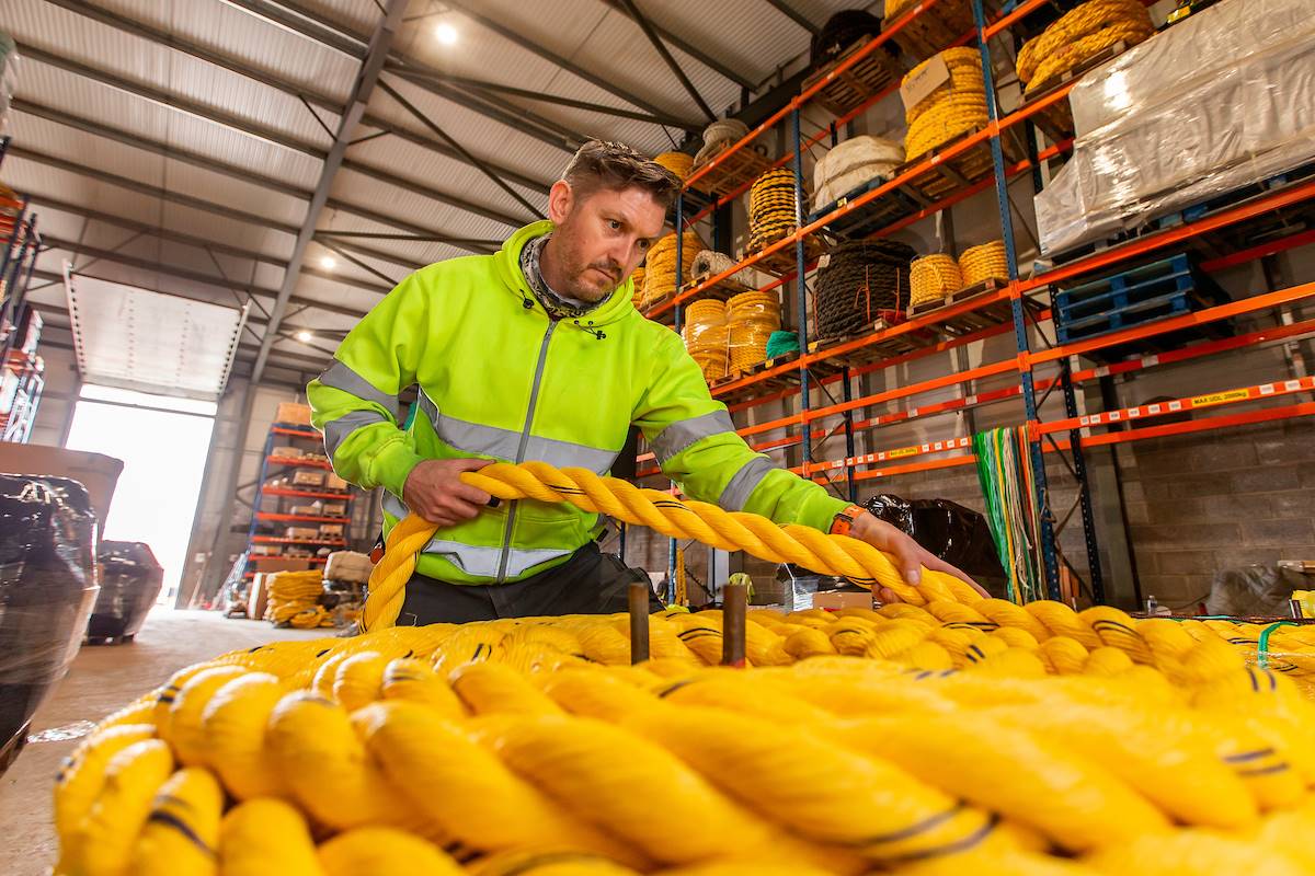 Employee at Gael Force group working with bright yellow, thick ropes wearing high vis yellow jacket